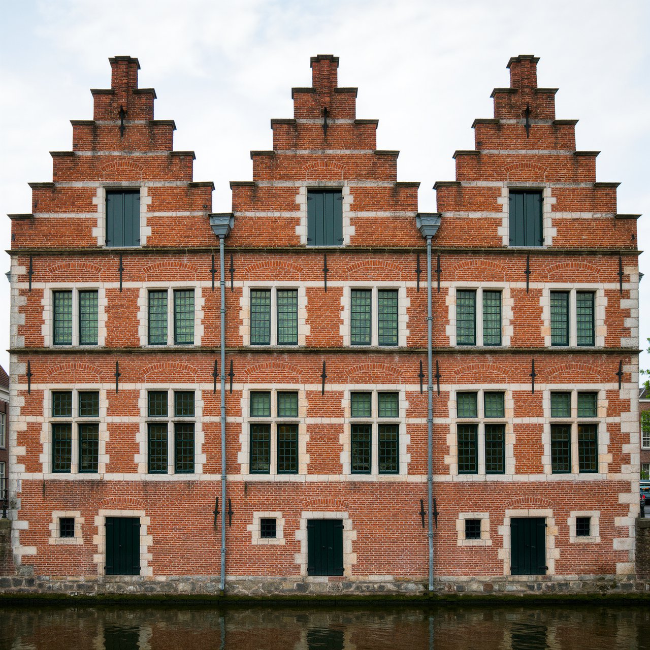 Exterior of a Dutch Renaissance canal-side archive, with warm red brick, pale stone bands, stepped gables, and tall sash windows; soft overcast light reveals the masonry, viewed from the opposite quay, with convincing structure and precise architectural lines. — Kling v3 Omni