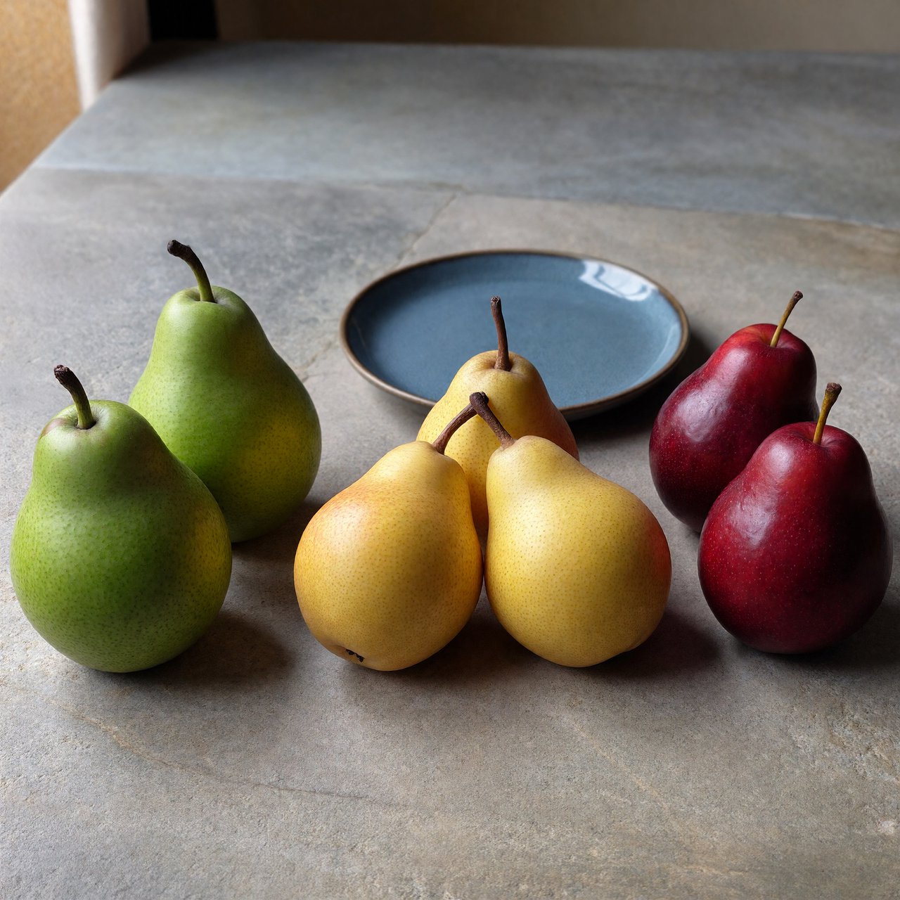 Exactly six ripe pears sit on a pale stone counter: two green pears on the left, two yellow pears in the center, and two red pears on the right. A small blue plate sits above the center pair, nothing else. — ImagineArt 1.5 Pro