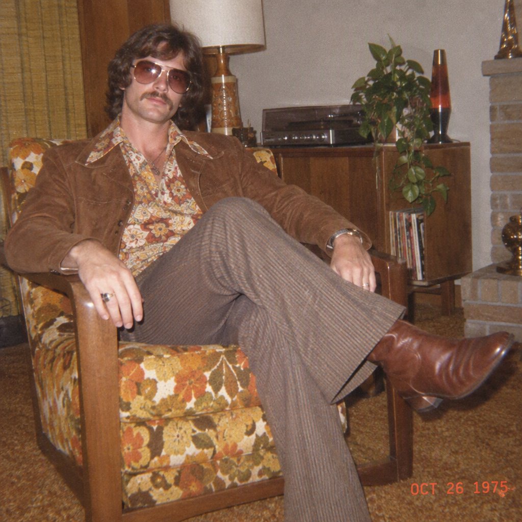 Create an image of a man in the quintessential style of 1975. Style his hair, clothing, accessories, and surroundings to reflect the distinctive look of the mid-1970s—featuring bold silhouettes, eye-catching accessories, layered details, and characteristic colors and textures. Give the image the feel of an authentic 1975 photograph, complete with analog film grain, faded colors, direct flash lighting, and a slight soft-focus effect. Add a period-accurate, red-orange date stamp in a 1970s style in one of the bottom corners. No recognizable posters. No modern objects or text. — GPT Image 2.5 Flare