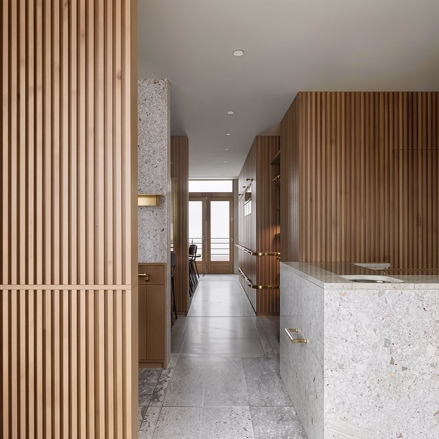 Inside an empty harbor café, restrained Danish modern design pairs ash slat screens, pale terrazzo, and brushed brass; overcast window light reaches the counter, viewed from the entrance, with aligned joinery and believable supports. — Model 9
