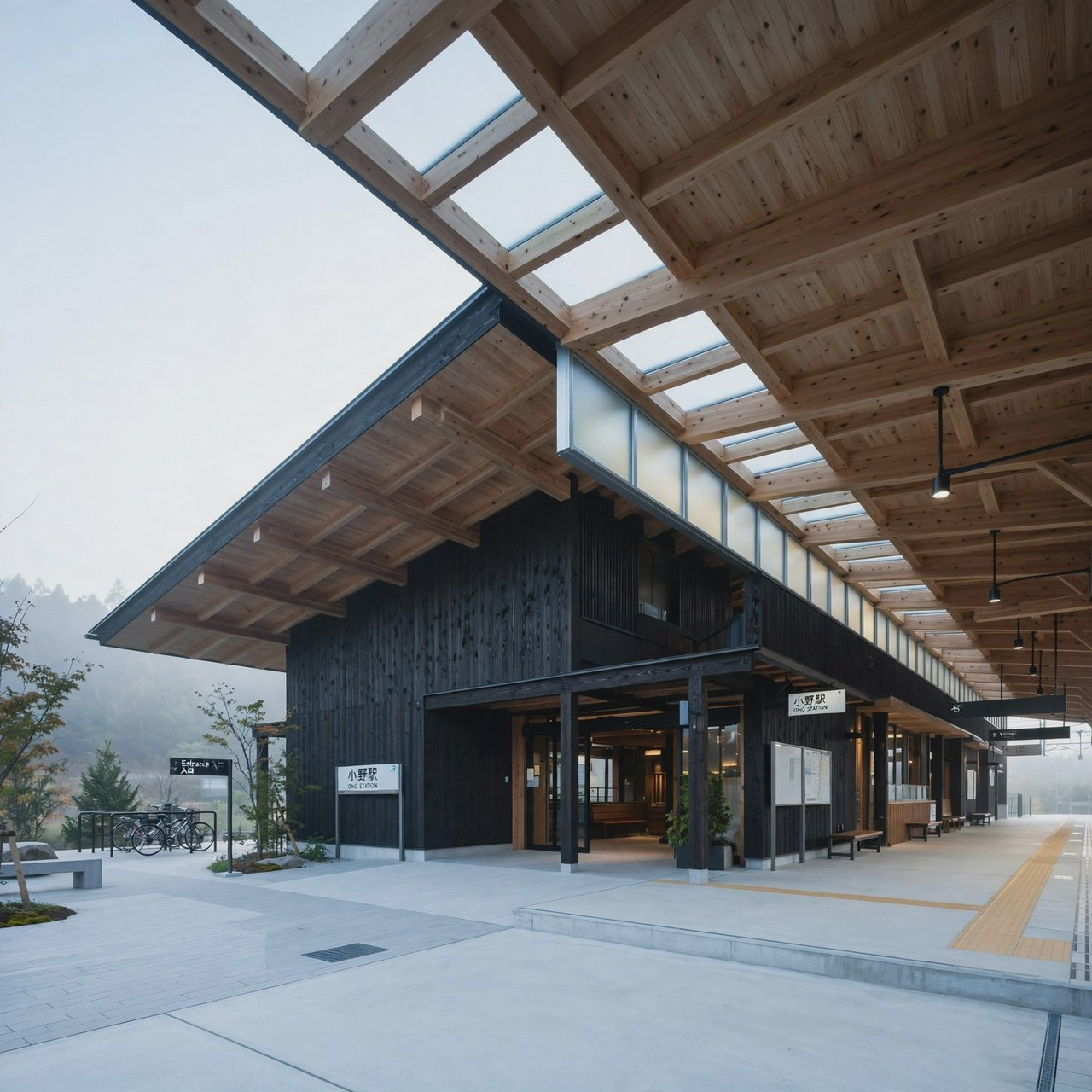 Contemporary Japanese timber train station, charred cedar cladding, pale concrete platform, broad pitched roof with exposed beams and translucent clerestories, cool morning light, viewed obliquely from the quiet approach plaza, precise straight lines and plausible structure. — Muse Image 1.0