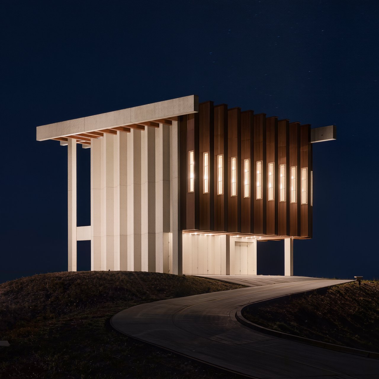 A hilltop observatory in spare contemporary architecture glows against the midnight sky, its pale concrete walls, bronze panels, and narrow windows lit from within; viewed from the access road, crisp edges and credible structural supports. — Kling v3