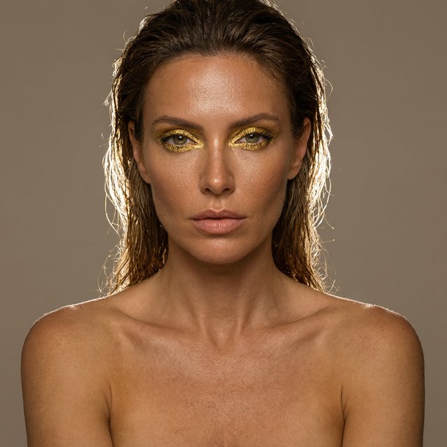Beauty close-up of an adult woman with bronzed skin and gold eye makeup, bare shoulders, studio backlight halo, high-end campaign look. — Qwen Image 3.0 Pro