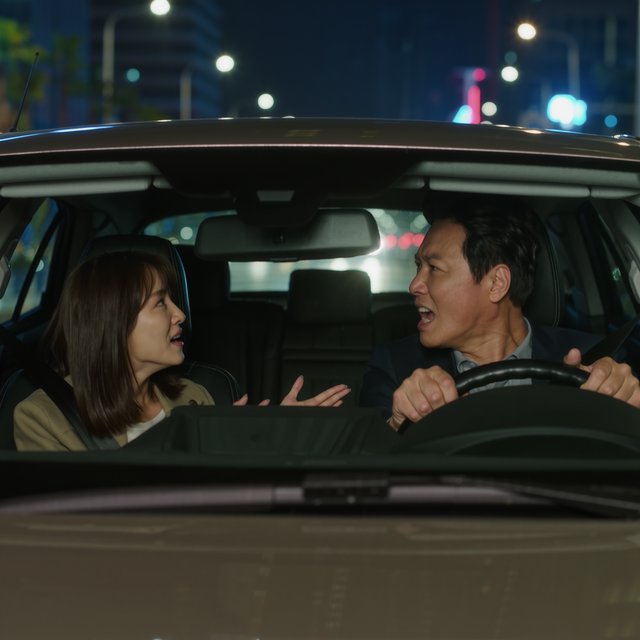 Frontal cinematic shot through the windshield of a car driving at night. A 35-year-old Chinese man is in the driver’s seat, gripping the steering wheel and arguing back in visible frustration. Beside him, a 30-year-old Chinese woman in the front passenger seat is nagging him animatedly, gesturing as she speaks. Both are clearly engaged in a tense argument. Nighttime city lights and passing streetlights glow outside, with reflections across the windshield and realistic interior lighting. — Kling v3 Omni