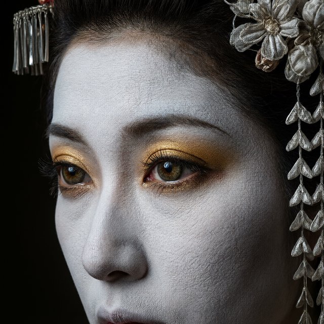 Extreme close-up macro photography of a Geisha's face. The focus is on her eyes, revealing intense emotion and hyper-realistic detail. Her skin is covered in traditional white 'Oshiroi' makeup, showing subtle, realistic cracking and skin texture. Dramatic Chiaroscuro lighting with deep shadows and a single soft light source highlighting the shimmer in her golden eyeshadow and the wetness of her eyes. Ornate kanzashi (hair ornaments) visible in the blurred periphery with intricate silk flowers and dangling silver petals. Cinematic composition, shot on 100mm macro lens, incredibly detailed eyelashes and iris patterns. — Model 17