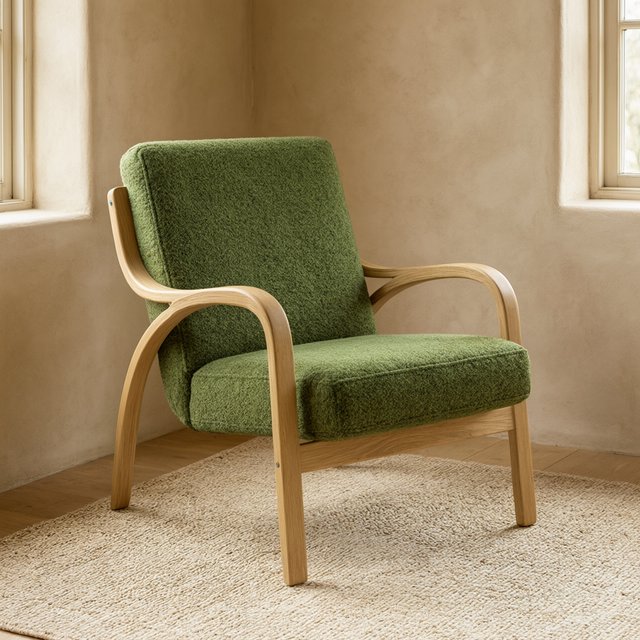 In a quiet reading-room corner, an unbranded lounge chair pairs a curved ash frame with nubby moss-green wool upholstery, set on a pale jute rug before a warm plaster wall; broad window diffusion and soft bounce shape this commercial product image, with no lettering. — Qwen Image 3.0 Pro