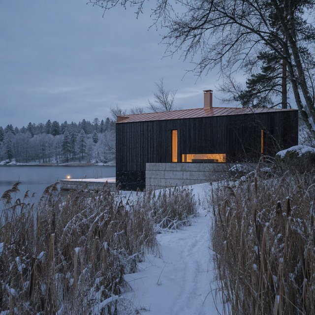 Exterior of a Scandinavian modernist lakeside sauna pavilion, blackened timber cladding, pale granite plinth, copper roof, winter blue-hour light glowing through narrow windows, viewed from a snowy reed-lined path, straight structural geometry and plausible construction. — GPT Image 2.5 Sunburst