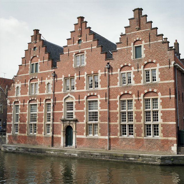 Exterior of a Dutch Renaissance canal-side archive, with warm red brick, pale stone bands, stepped gables, and tall sash windows; soft overcast light reveals the masonry, viewed from the opposite quay, with convincing structure and precise architectural lines. — Ideogram v4.5