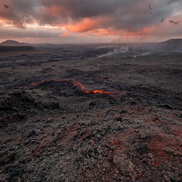 Fresh lava threads a black cinder plain on a volcanic island at dusk beneath ash-laden wind; blistered crust and brittle pumice in the foreground give way to glowing fissures fading into smoke. — Krea 2 Large
