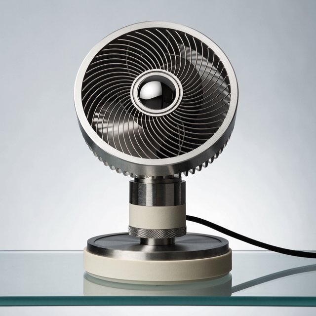 Commercial product photograph of an unbranded desktop fan made from brushed aluminum and matte ivory polymer, resting on a smoked glass surface against a pale gray background, illuminated by broad diffused studio light and a soft rear rim light. — Recraft v4