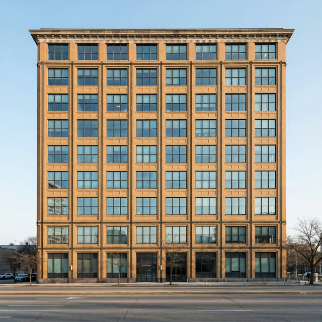 Exterior of a Chicago School office tower, with a visible steel-frame grid, warm terra-cotta cladding, broad rectangular windows, and a flat roofline; clear afternoon light, viewed from across a city street, with precise verticals and believable construction. — Ideogram v4.5