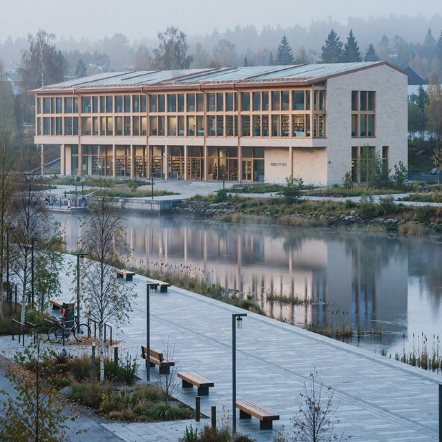 A riverside public library in contemporary Nordic brick architecture combines pale buff brick, oak-framed glazing, and a copper roof; cool morning light grazes its elevations, viewed from across the promenade, with straight lines and credible supports. — Model 14