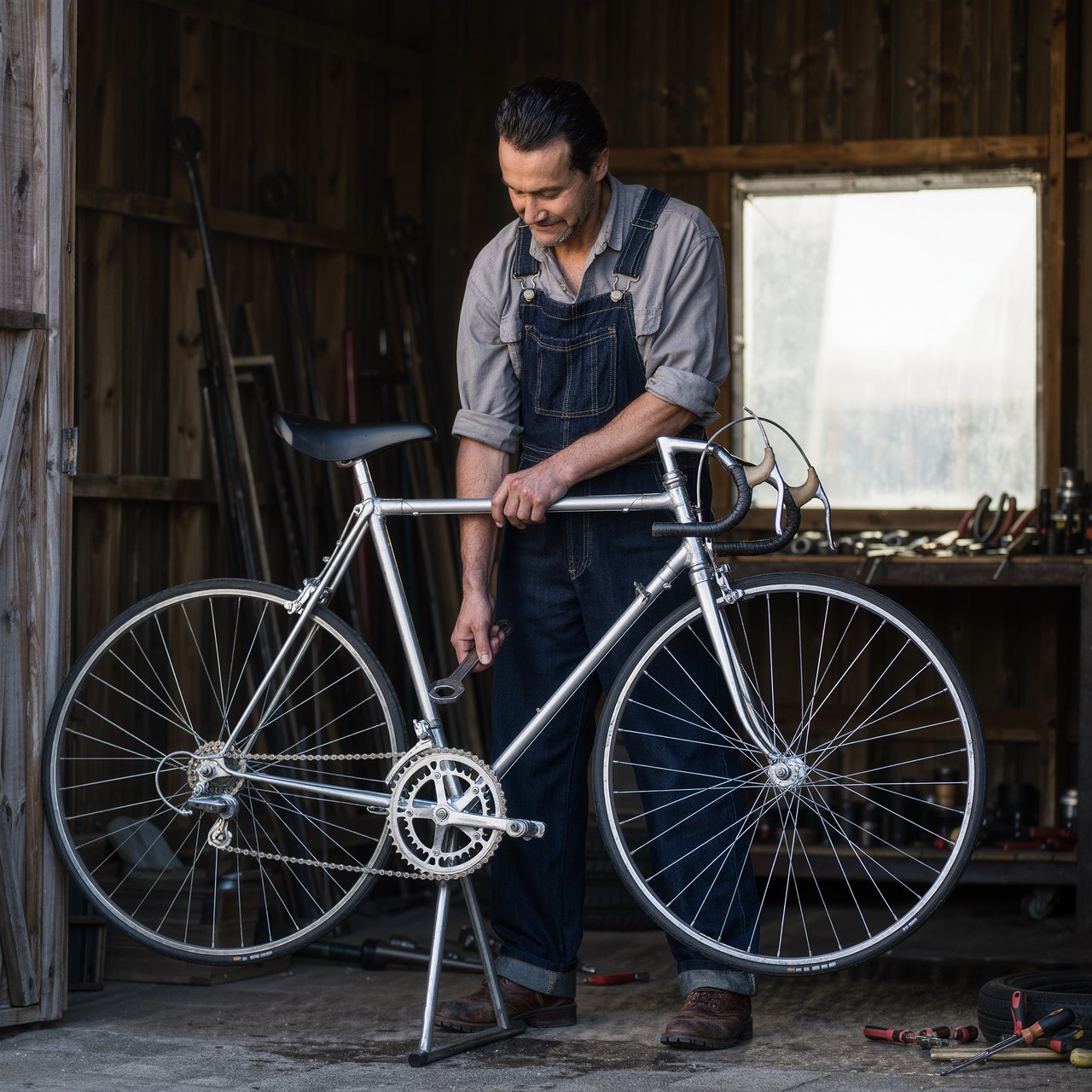 Candid documentary photograph of an adult repairing a bicycle at a quiet curbside workshop, cool morning window light, 50mm lens with shallow depth of field, grease smudges on their fingertips. — Kling v3 Omni