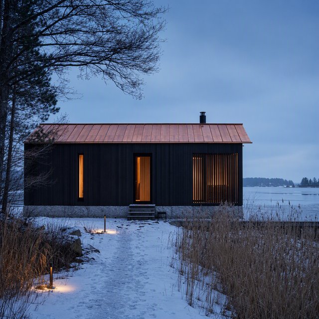 Exterior of a Scandinavian modernist lakeside sauna pavilion, blackened timber cladding, pale granite plinth, copper roof, winter blue-hour light glowing through narrow windows, viewed from a snowy reed-lined path, straight structural geometry and plausible construction. — GPT Image 2