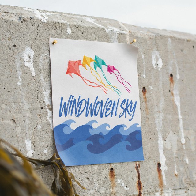On a salt-stained seawall, a printed poster for a kite-making exhibition shows bright diamond kites sweeping above blue waves; “WINDWOVEN SKY” is screen-printed in sweeping cobalt script, with no other legible writing. — Model 7