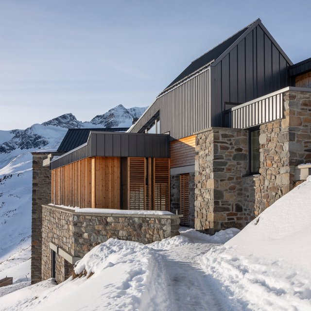 Exterior of a contemporary alpine research lodge in restrained regional modernism, rough granite walls, larch screens, steep standing-seam roof, crisp snow-bright morning light, viewed from below across a mountain footpath, sound structural geometry. — ImagineArt 2
