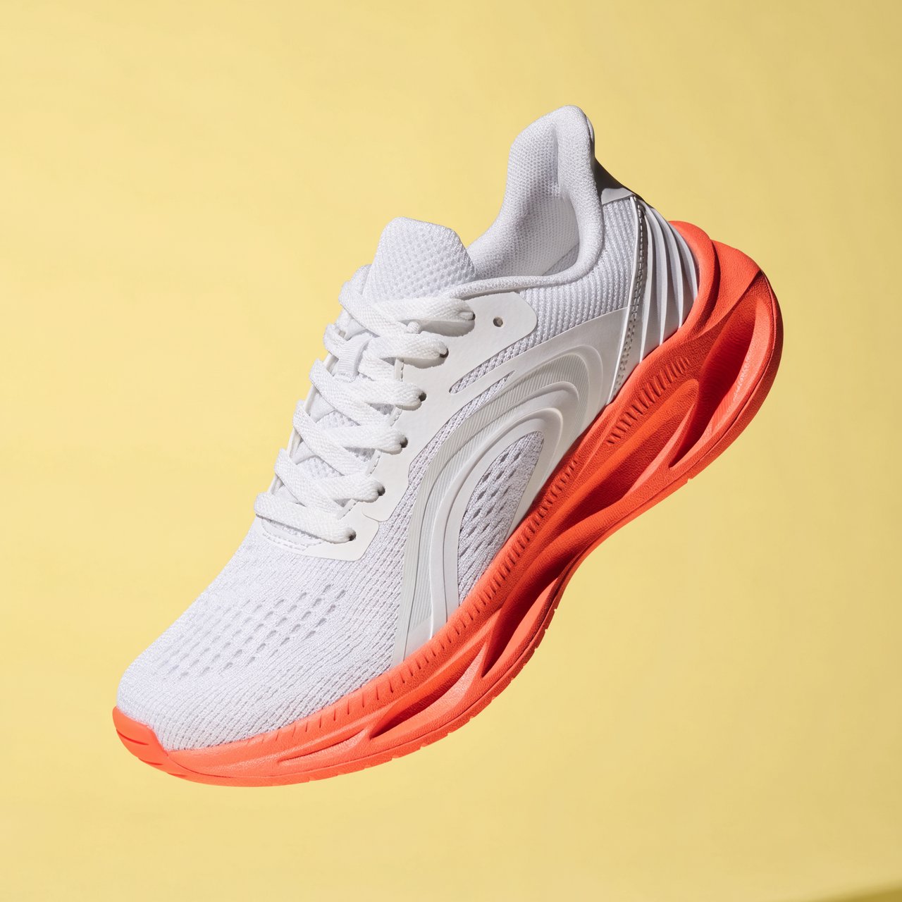 A white running sneaker with a coral sole floating at a slight angle over a pastel yellow background, studio lighting, no shadow on the backdrop. — Recraft v4 Pro