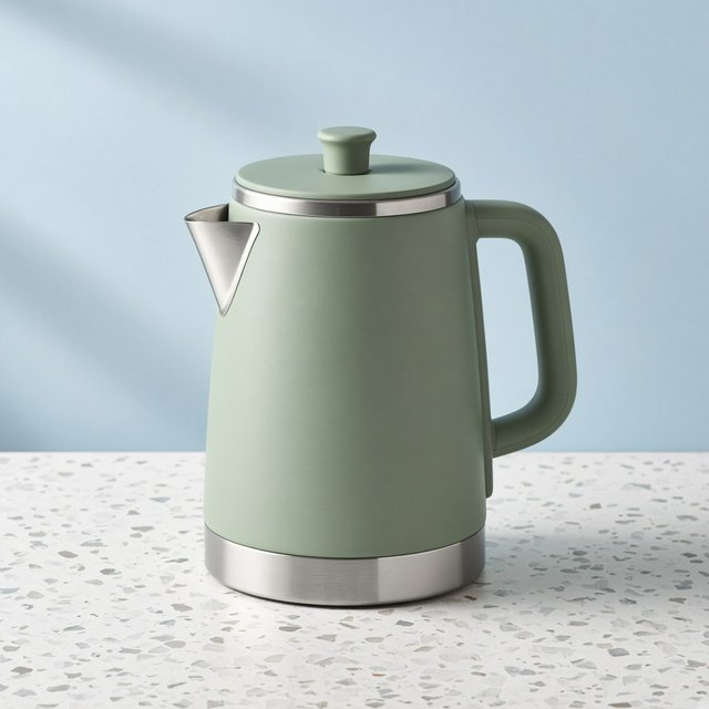 Commercial product photograph of an unbranded electric kettle made from matte sage ceramic and brushed stainless steel, resting on a white terrazzo surface against a pale blue background, with soft window light from the left and a delicate grounding shadow. — Grok Imagine Image 2