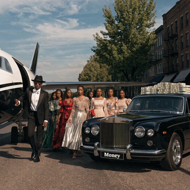 A man dressed in very nice formal clothes is getting off a private black-and-white plane. Many beautiful adult women in dresses are following the man. The man is heading toward a very high-end classic black car. The word "Money" is on the car's license plate. On top of the car is a ton of money. It is the afternoon. The vibe is cool and rich. — Recraft v4