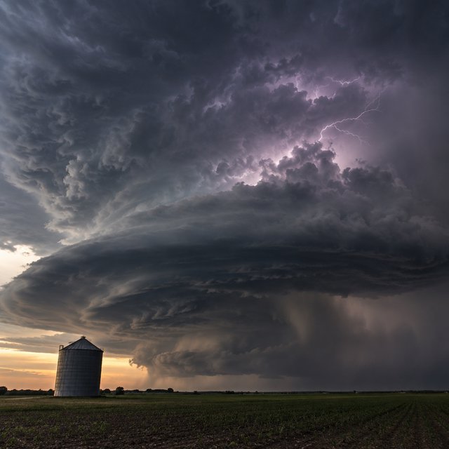 A supercell thunderstorm over flat farmland, lightning inside the cloud, a lone grain silo, dramatic but realistic. — GPT Image 2.5 Sunburst