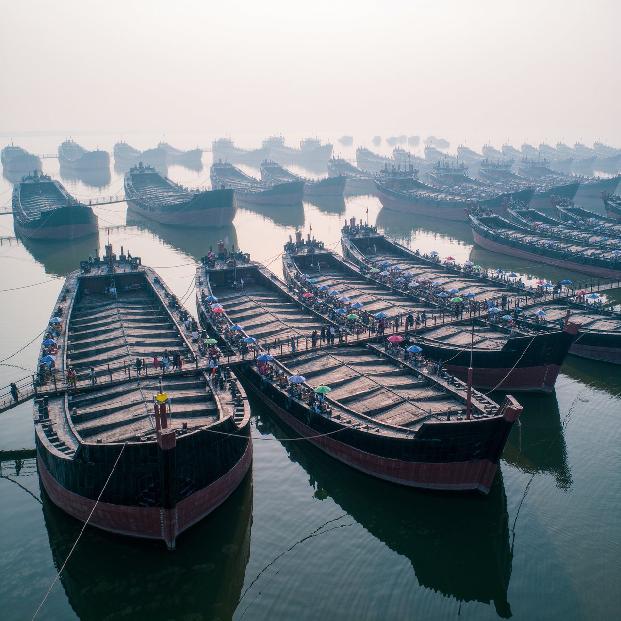A floating market city built on the hulls of giant upturned ships, rope bridges, morning haze, wide establishing shot. — Kling v3 Omni