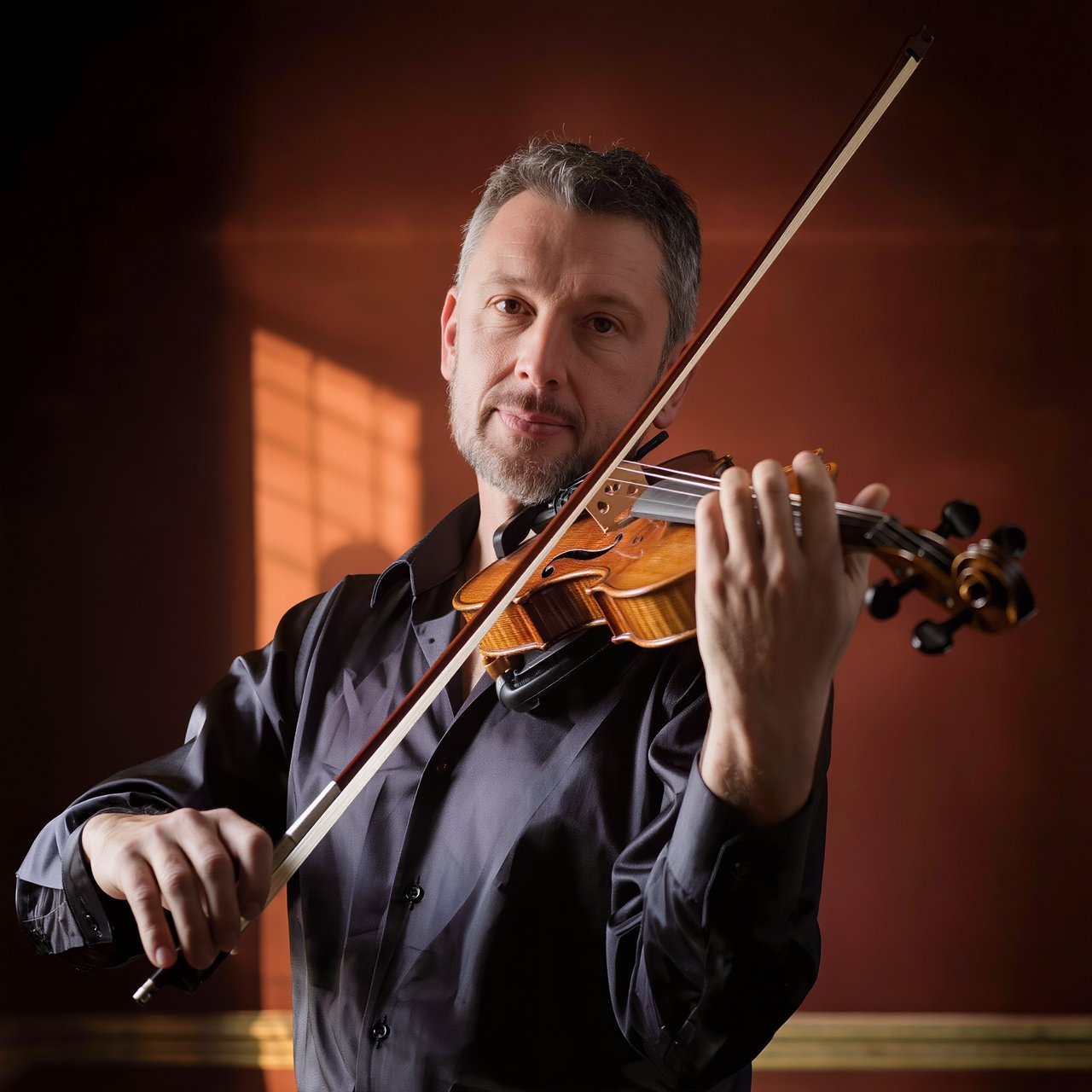 With a violin tucked close, an adult man in his early 50s draws a bow, his hands prominent, wearing a charcoal silk shirt; his intent expression is framed against a warm umber backdrop in soft amber window light, in a close portrait photograph. — Kling v3