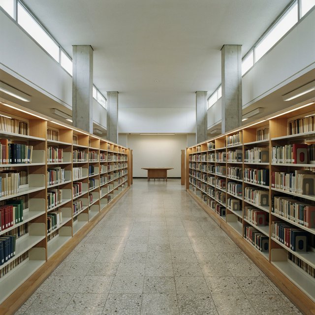 Interior of a mid-century modernist public library, with pale oak shelving, exposed concrete columns, terrazzo flooring, and a broad clerestory. Diffuse morning light crosses the reading hall, viewed from the entrance down its central aisle, with precise lines and plausible structure. — Ideogram v4.5