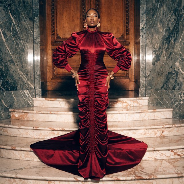 An adult woman in a floor-length red satin evening gown on a marble staircase, soft key light, confident pose, magazine cover style. — Recraft v4