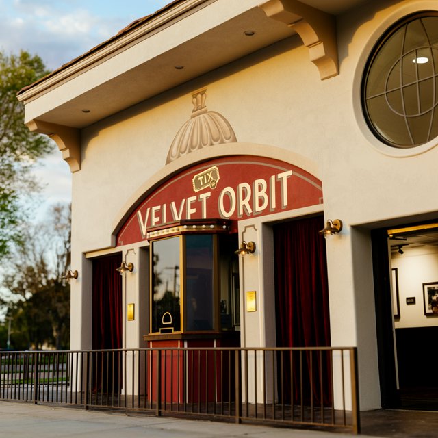 In a restored neighborhood cinema, brass sconces illuminate velvet curtains and a glass ticket booth; "VELVET ORBIT" is painted in ivory block letters across the booth’s burgundy fascia. — Krea 2 Large