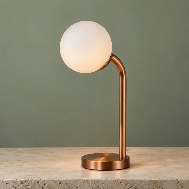Commercial product photograph of an unbranded sculptural desk lamp with a frosted opal glass globe and brushed copper stem, standing on a pale travertine surface against a muted sage background, illuminated by soft overhead diffusion and a delicate warm rim light. — GPT Image 2.5 Flare