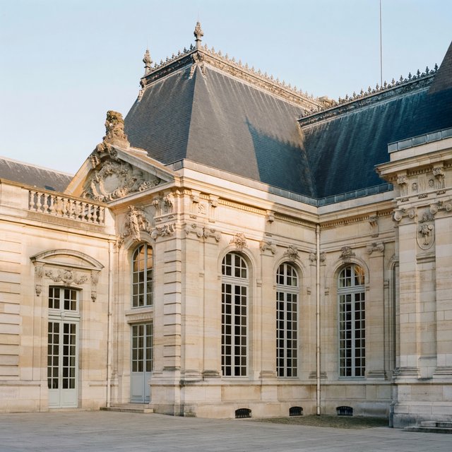 Exterior of a French Second Empire town hall with pale limestone, a dark mansard roof, copper cresting, and tall arched windows; clear spring light falls across the entrance terrace, viewed from the quiet street corner, precise lines and believable construction. — ImagineArt 2