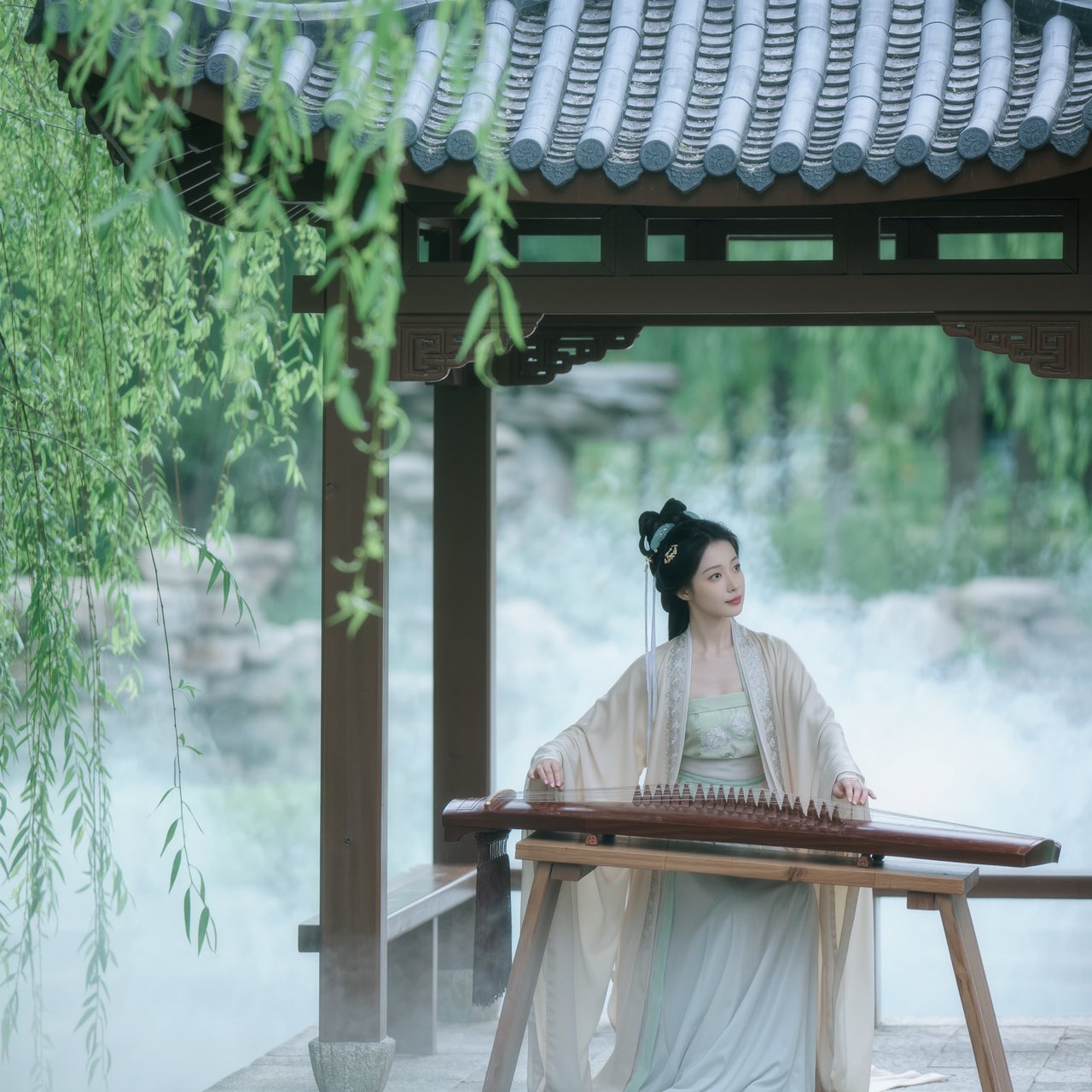 An elegant ancient Chinese lady in hanfu plays the guzheng in a quiet garden pavilion, surrounded by willow trees and mist, creating a poetic atmosphere. — Kling v3 Omni