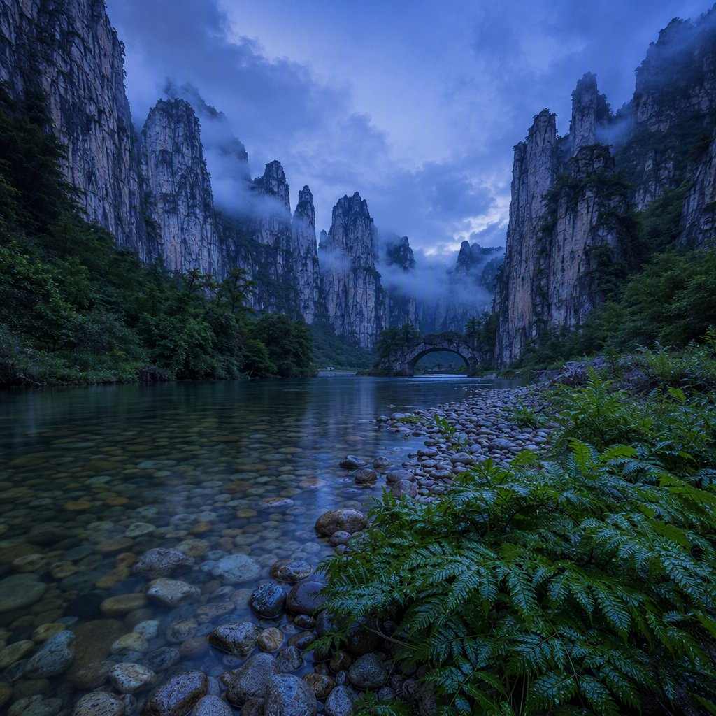 A limestone karst valley at blue hour after a light shower, towering pale cliffs rising above a clear river, low clouds snagging on pinnacles, slick ferns and rounded pebbles leading toward a distant stone arch. — GPT Image 2