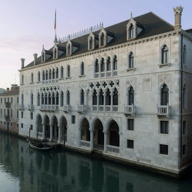 Exterior of a Venetian Gothic opera house beside a quiet canal, pale Istrian limestone, pointed arches, quatrefoil tracery, and a steep slate roof; cool morning light, viewed from across the water, crisp masonry lines and believable structure. — Grok Imagine Image Quality