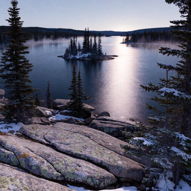 An expansive boreal lake beneath a clear, cold midnight sky, pale moonlight catching thin mist above dark water; spruce-covered islands recede toward distant ridges, while lichen and cracked granite sharpen the near shoreline. — Recraft v4 Pro