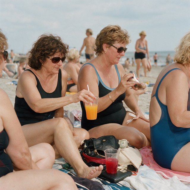 A realistic scene of women in one-piece swimsuits on the beach, with a peaceful vibe, orange and red drinks nearby, high-quality items nearby, a bit of money also nearby, and many angles. — Seedream 5.0 Pro