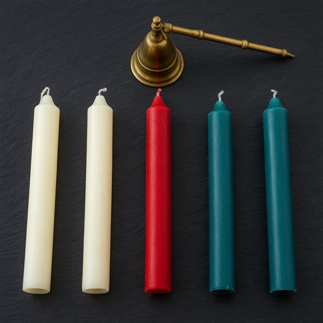 Exactly five candles stand on a dark slate tabletop: two ivory candles on the left, one red candle in the center, and two teal candles on the right. A brass snuffer sits above the red candle, nothing else. — Qwen Image 3.0