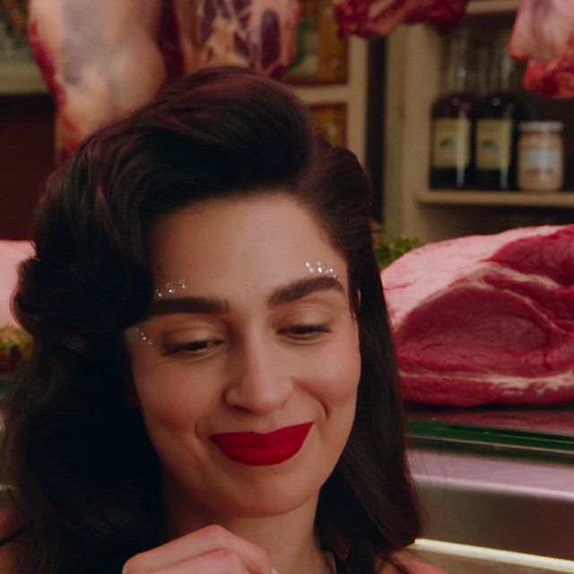 Happy glamorous woman examining meat in a butcher shop. — Krea 2 Medium
