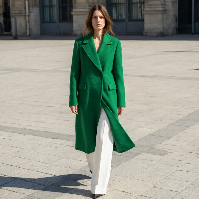 Full-length fashion editorial: model in a structured emerald wool coat and white trousers walking across a wide empty plaza, harsh midday sun, long shadow. — Qwen Image 3.0 Pro