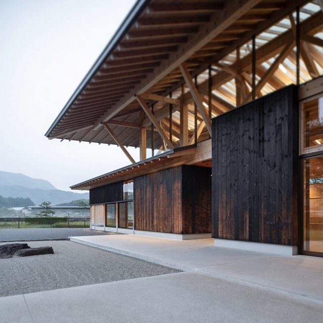 Contemporary Japanese timber train station, charred cedar cladding, pale concrete platform, broad pitched roof with exposed beams and translucent clerestories, cool morning light, viewed obliquely from the quiet approach plaza, precise straight lines and plausible structure. — ImagineArt 2