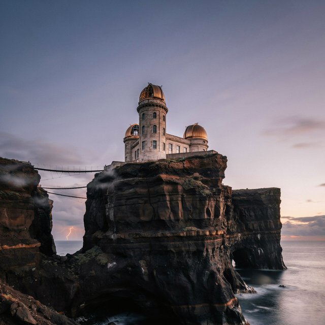 A wind-carved observatory crowns black cliffs above a silver inland sea, its open brass domes catching the last rose light. Salt mist drifts through suspended bridges as distant storms flicker beyond the horizon. — Ideogram v4.5