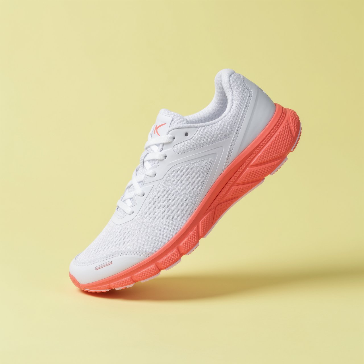 A white running sneaker with a coral sole floating at a slight angle over a pastel yellow background, studio lighting, no shadow on the backdrop. — Kling v3 Omni