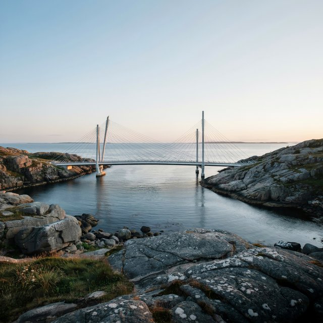 Across a sheltered coastal inlet, a contemporary high-tech cable-stayed bridge spans between granite shores, its slender steel pylons and pale concrete deck catching cool sunrise light; viewed from a rocky bank, straight lines and credible engineering define the scene. — Ideogram v4.5
