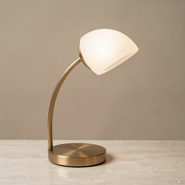 Commercial product photograph of an unbranded sculptural desk lamp made from brushed brass and opal glass, resting on pale travertine, against a warm gray background, with soft diffused light from upper left and gentle grounding shadow. — Ideogram v4