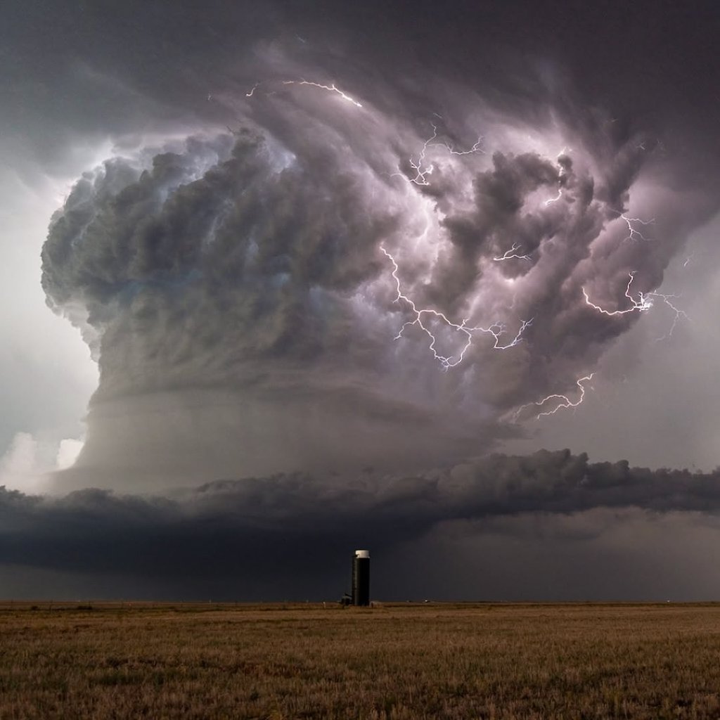 A supercell thunderstorm over flat farmland, lightning inside the cloud, a lone grain silo, dramatic but realistic. — Krea 2 Large