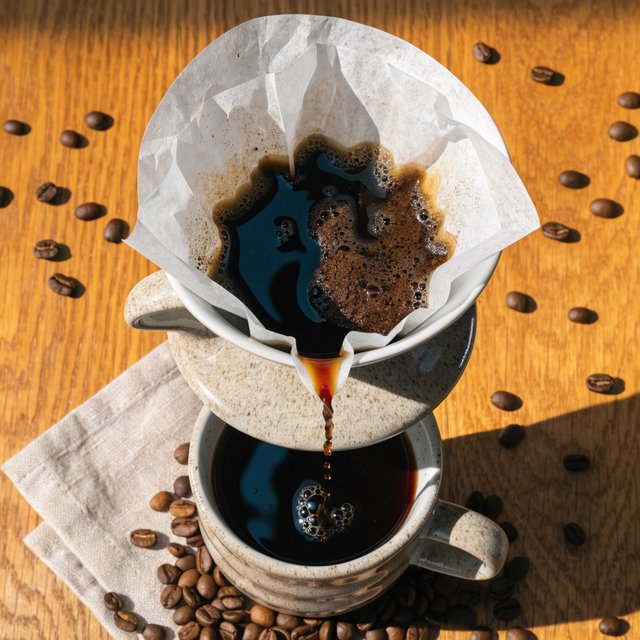 Overhead flat lay of a ceramic pour-over coffee set on oak, roasted beans scattered, a folded linen napkin, warm natural light. — Recraft v4