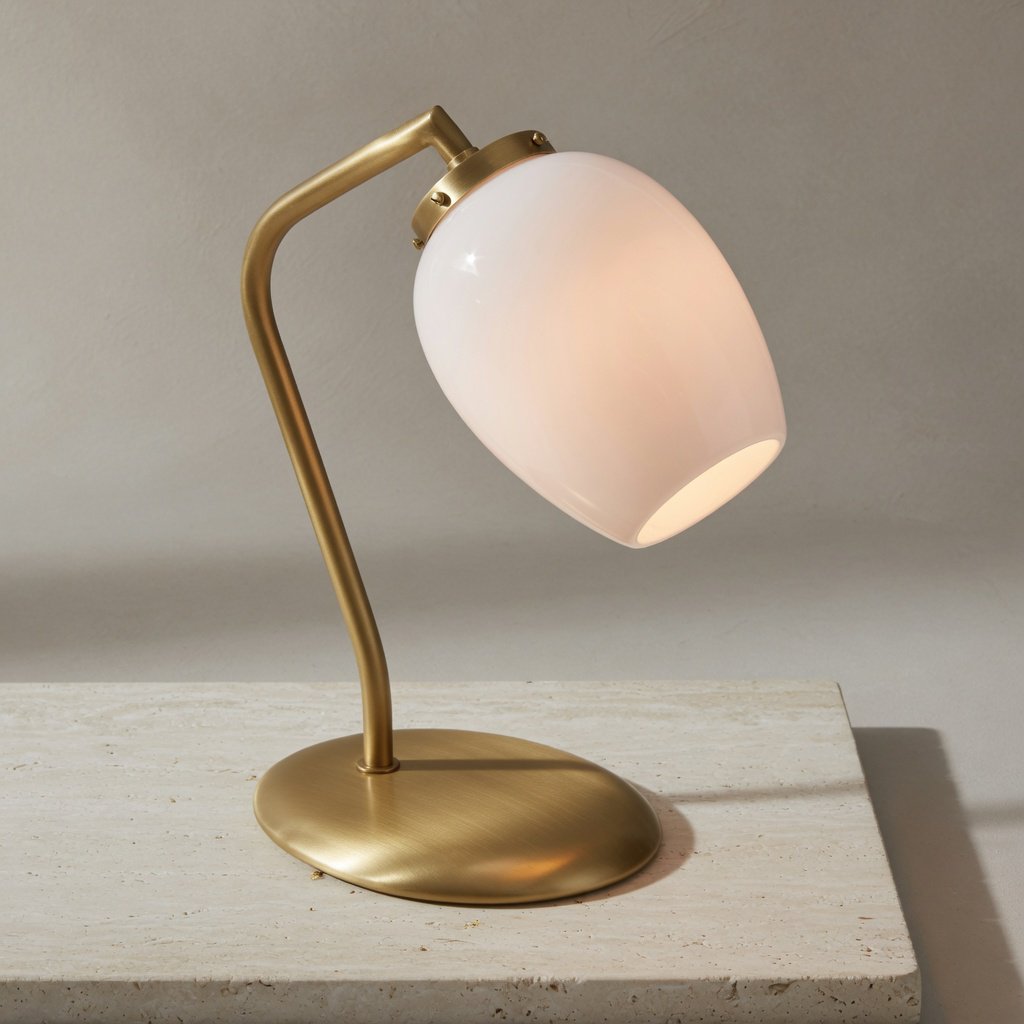 Commercial product photograph of an unbranded sculptural desk lamp made from brushed brass and opal glass, resting on pale travertine, against a warm gray background, with soft diffused light from upper left and gentle grounding shadow. — Grok Imagine Image Quality