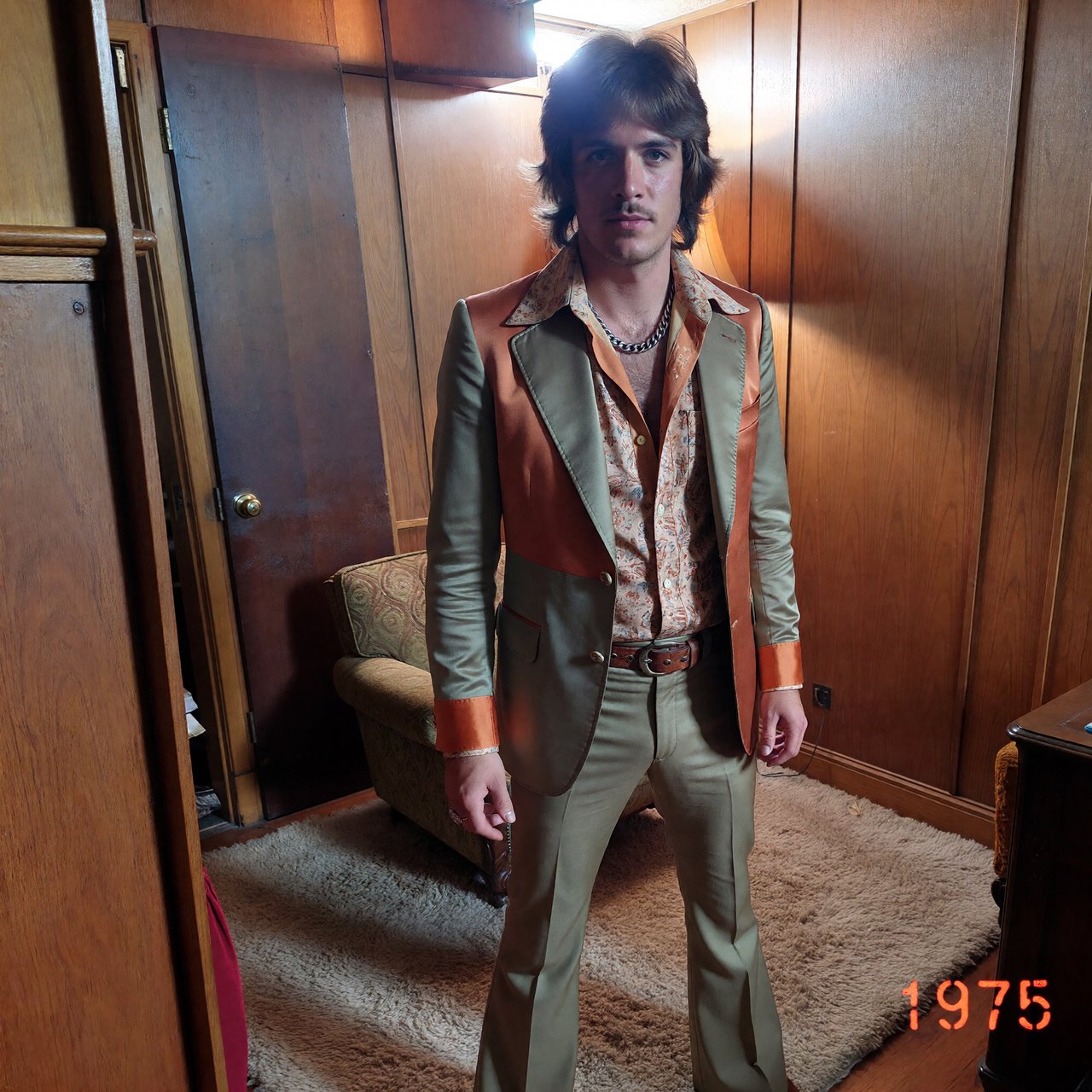 Create an image of a man in the quintessential style of 1975. Style his hair, clothing, accessories, and surroundings to reflect the distinctive look of the mid-1970s—featuring bold silhouettes, eye-catching accessories, layered details, and characteristic colors and textures. Give the image the feel of an authentic 1975 photograph, complete with analog film grain, faded colors, direct flash lighting, and a slight soft-focus effect. Add a period-accurate, red-orange date stamp in a 1970s style in one of the bottom corners. No recognizable posters. No modern objects or text. — ImagineArt 1.5 Pro
