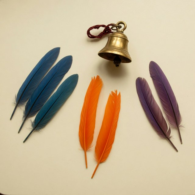Exactly seven feathers lie on a cream tabletop: three blue on the left, two orange in the center, and two purple on the right. A brass bell sits above the orange pair, nothing else. — Grok Imagine Image Quality