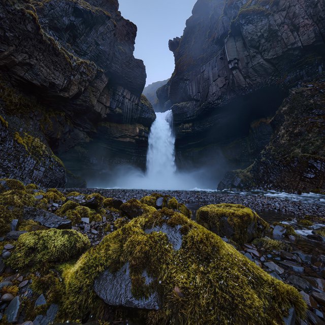 After a passing squall, a waterfall drops through a narrow basalt gorge at dusk, its white plume breaking against dark ledges; rain-beaded moss and sharp foreground stones lead toward cliffs fading behind drifting spray. — Kling v3